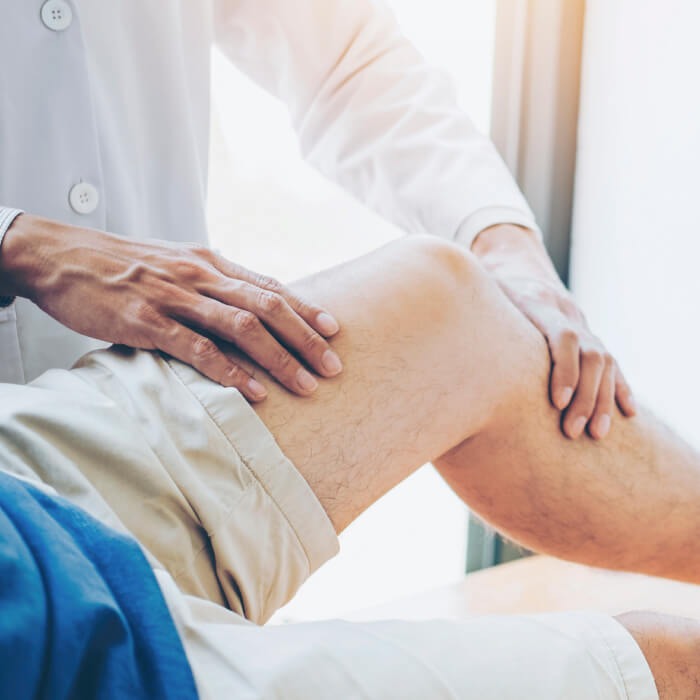 Doctor inspeccionando la rodilla de un paciente